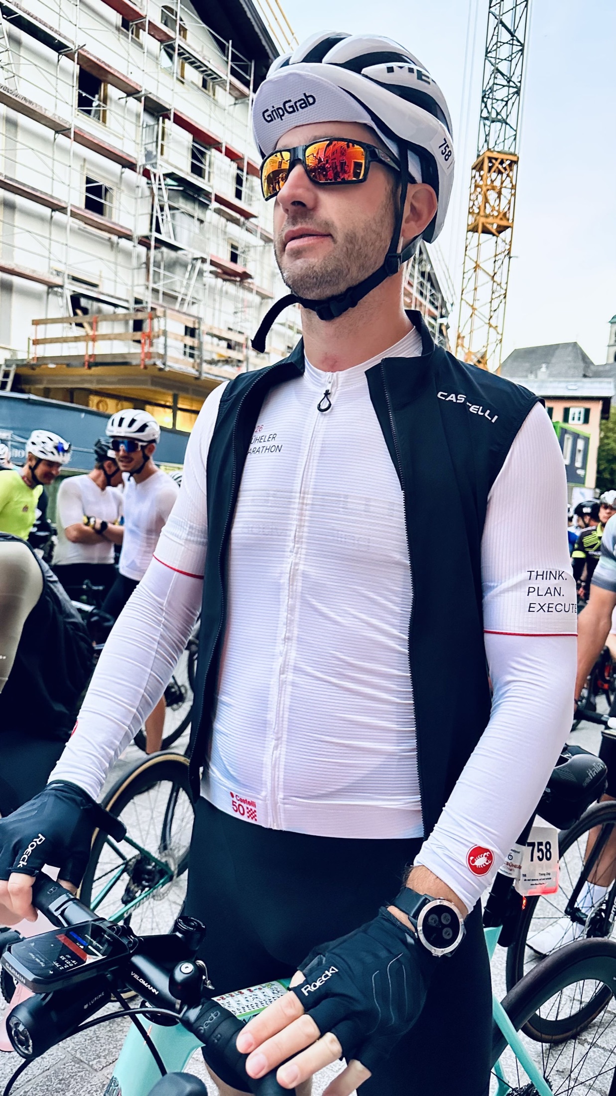 Christian mit weißem Helm und verspiegelter Sportbrille hält im Fahrerfeld den Lenker seines Rennrads.
