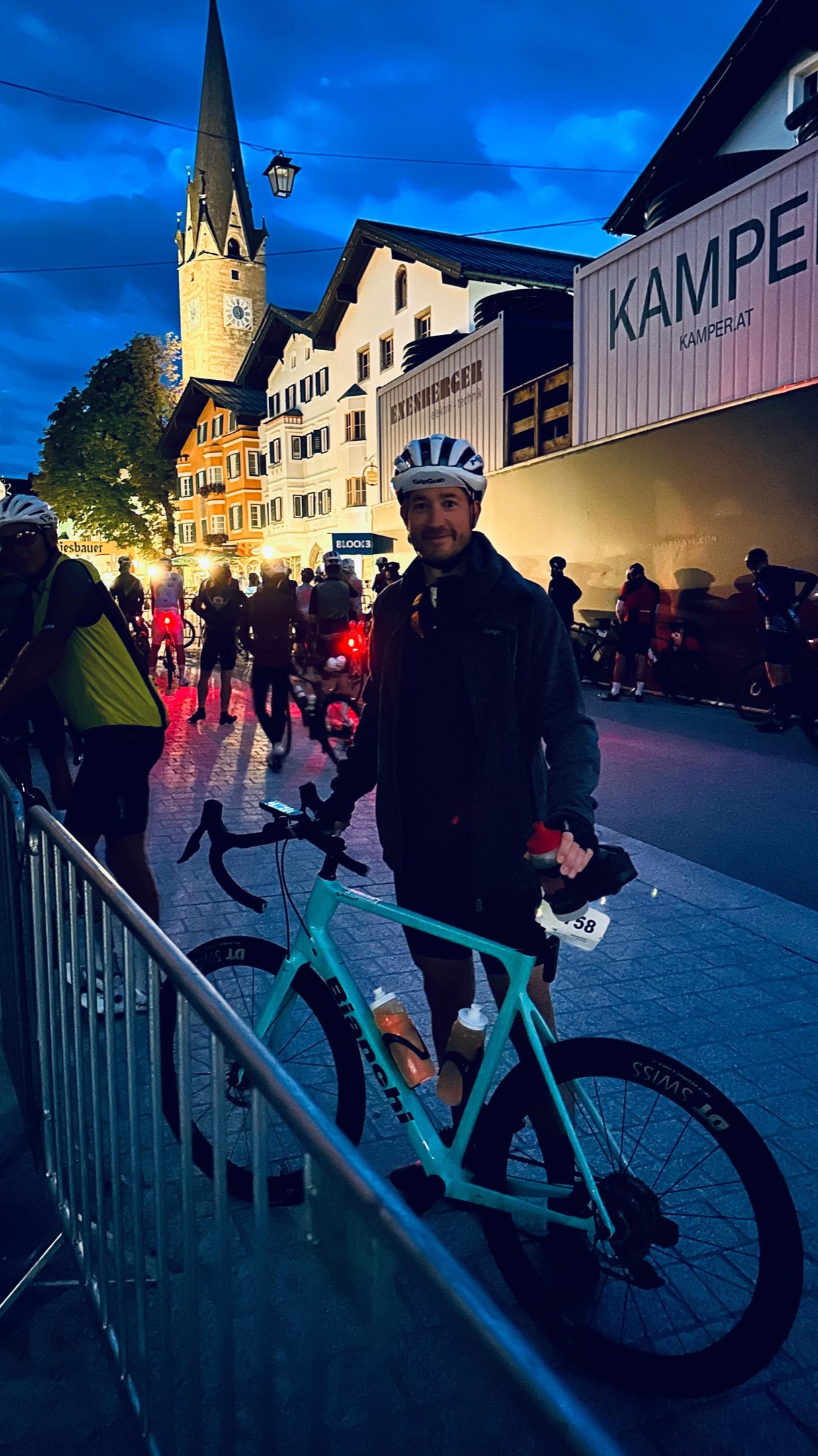 Christian steht bei Dunkelheit mit seinem türkisfarbenen Rennrad im beleuchteten Startbereich.