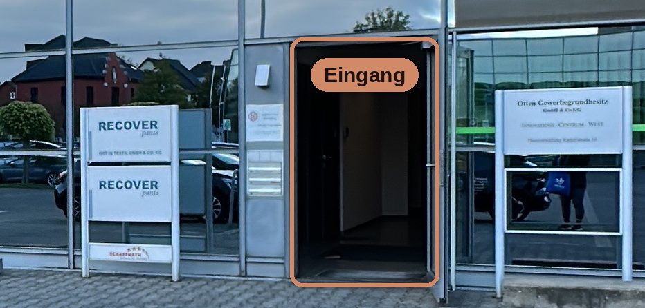 Nahaufnahme: offene Glastür zwischen dem Schild RECOVER pants und dem Schild Innovations-Centrum-West, als Eingang markiert.