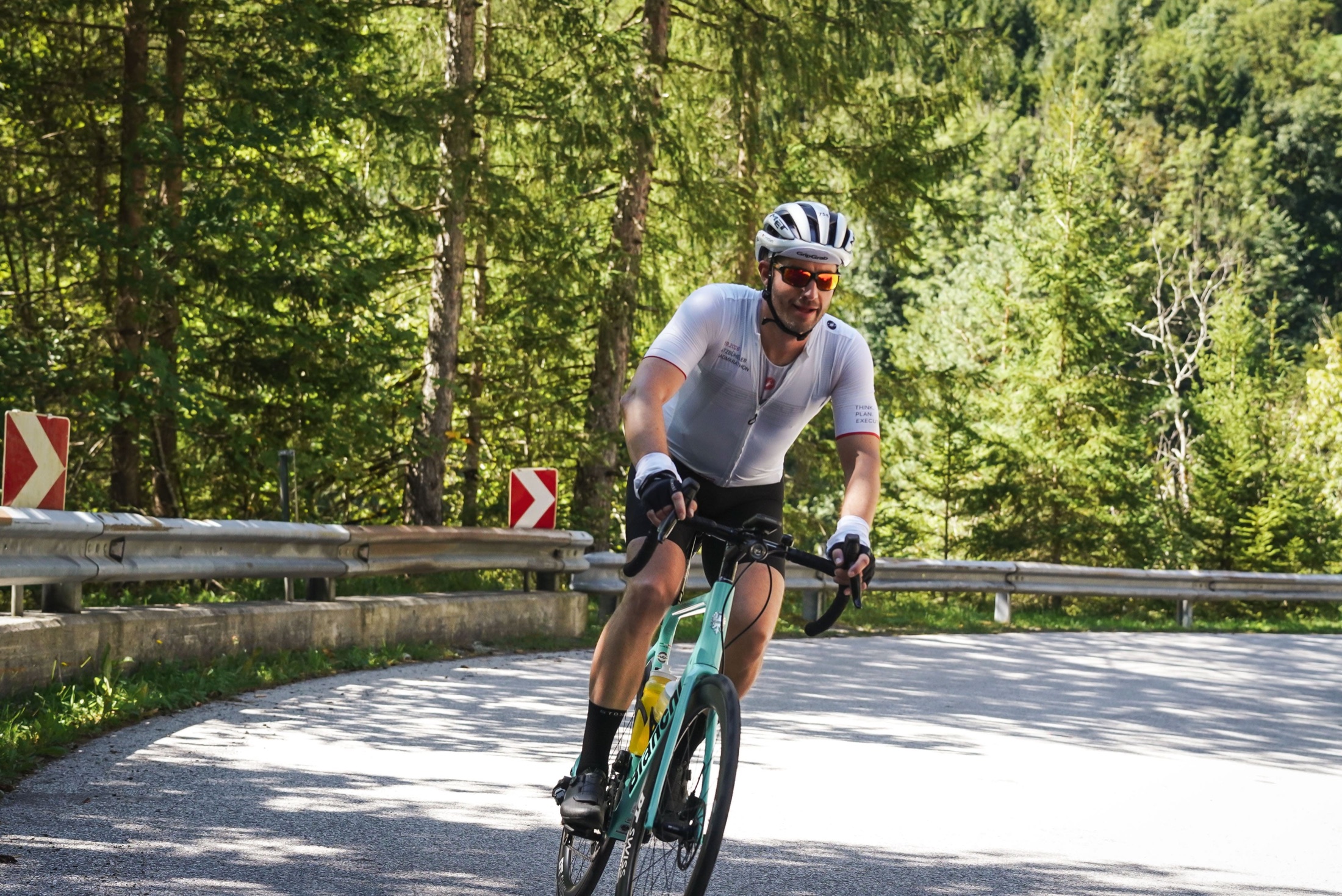 Christian fährt mit seinem Rennrad durch eine Kurve auf einer bewaldeten Bergstraße.